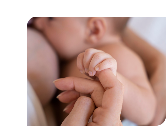 bebe qui allaite et tient la main de sa mère